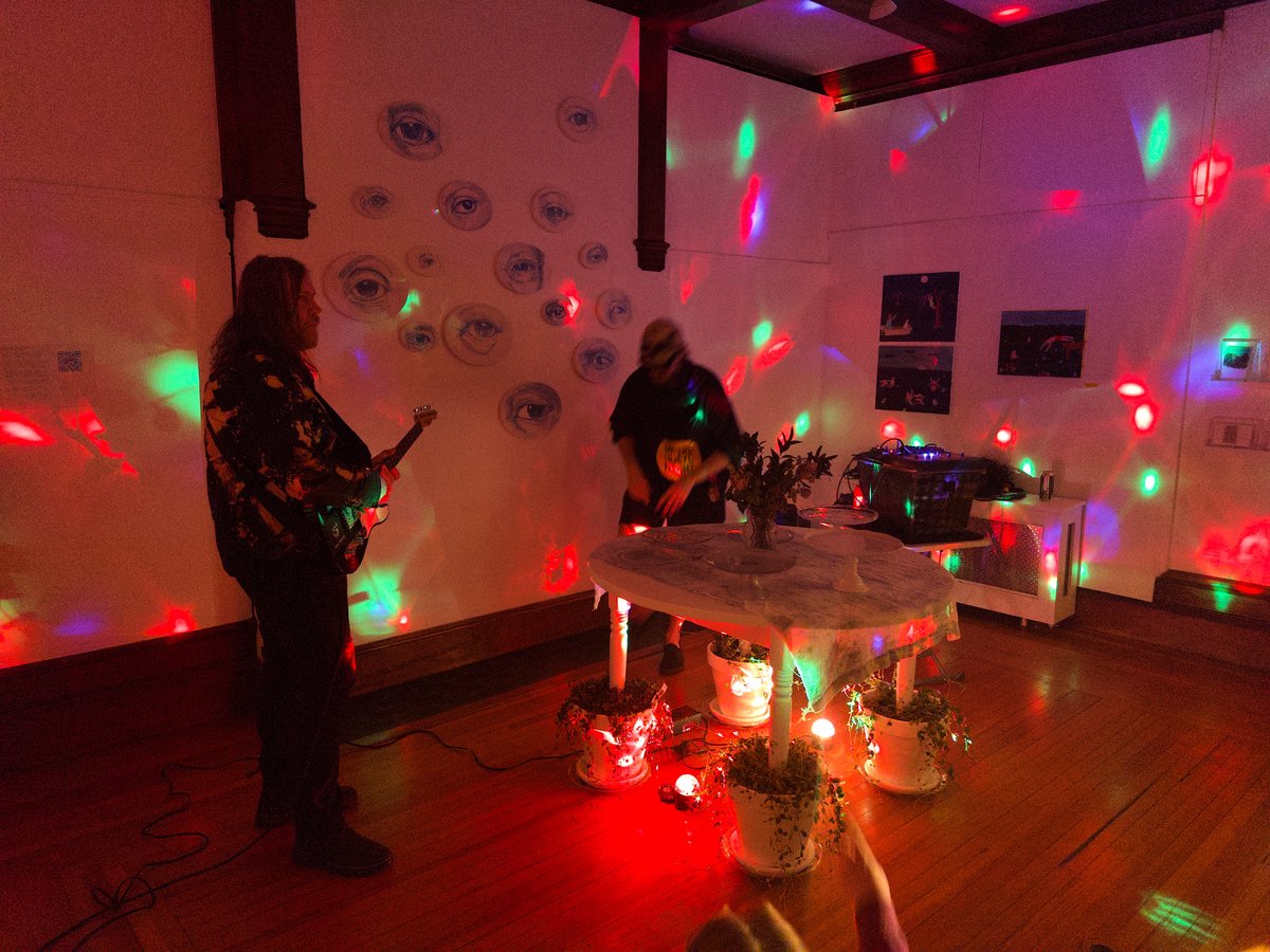 two people performing noise music in a room with rainbow lights