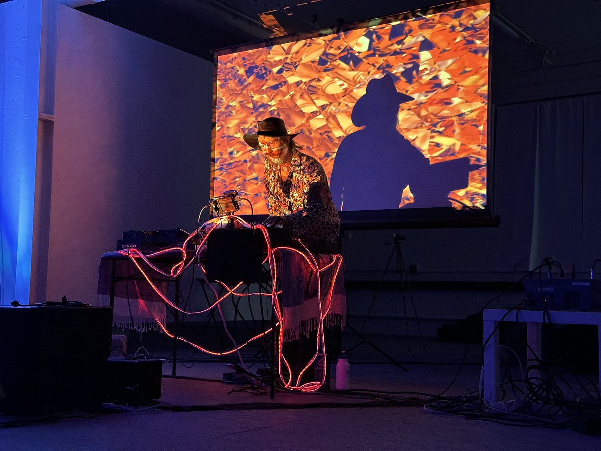 a person performing a dj set with projections and a cowboy hat