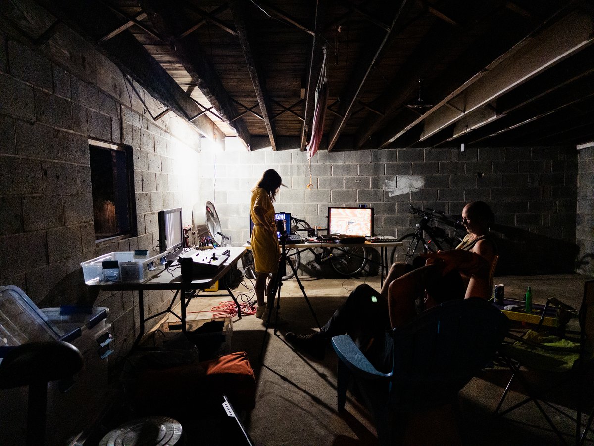 dark, high contrast image of people in a cinder block garage with tvs