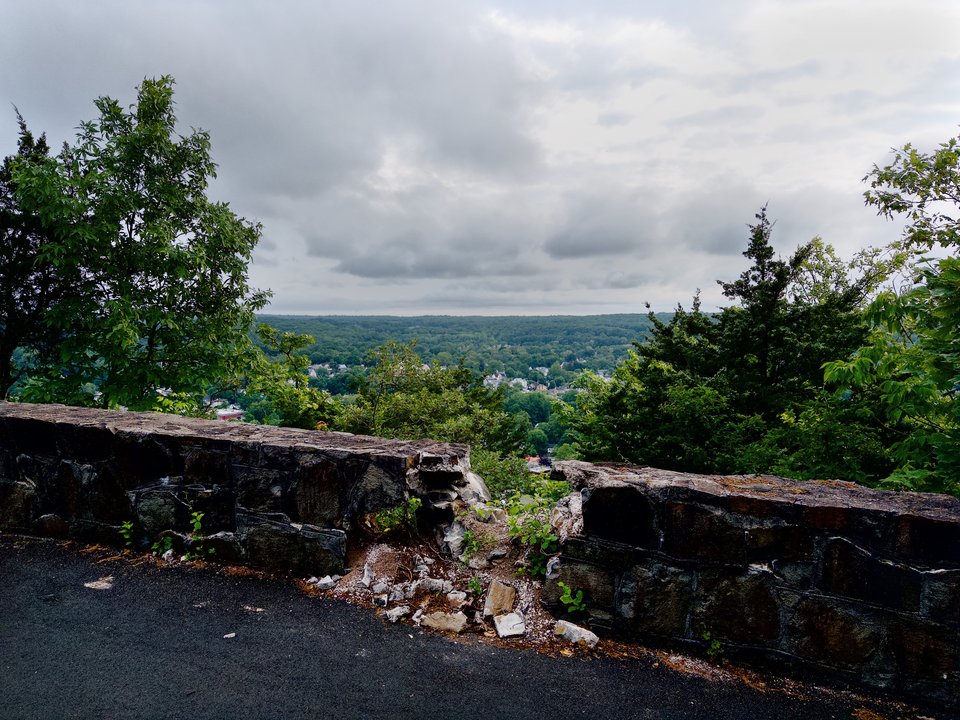 a crumbling stone wall overlooking a forested hill