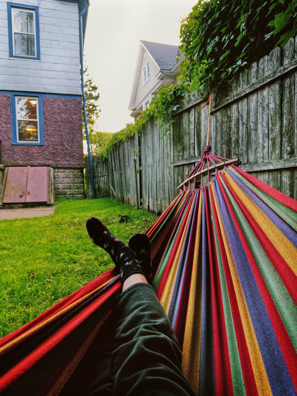 view from a fabric made with red and multicolored fabric. you can see grass, a fence, and the back of a house.