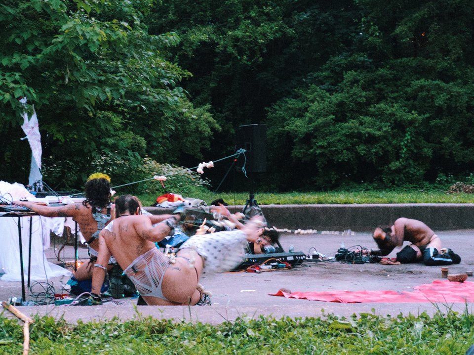 four people in costume in the park, crouched in various positions mid-dance