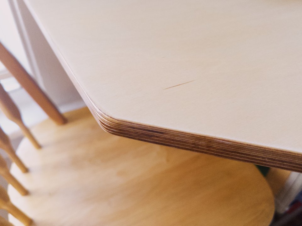 a close up image of the edge of a plywood tabletop, with a slightly rounded edge
