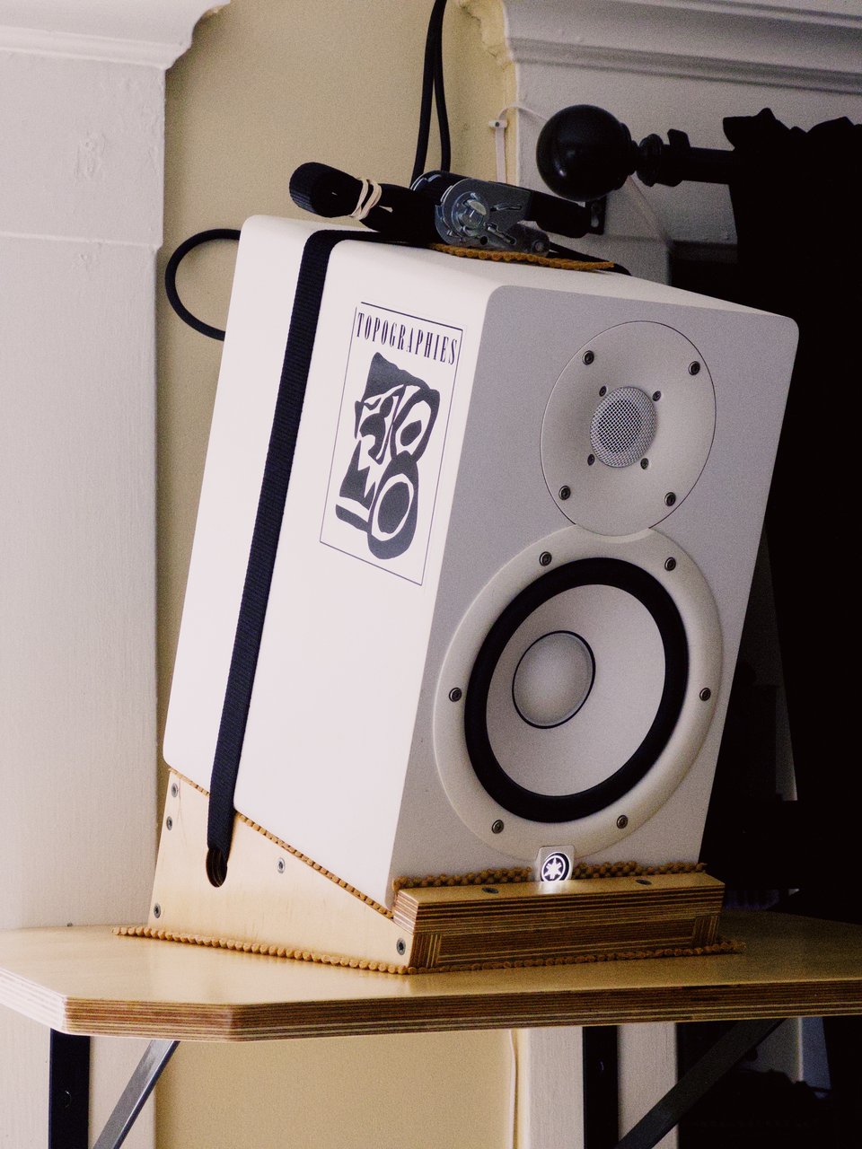 the same speaker, viewed from more of a three quarter angle, showing more of the angled plywood stand