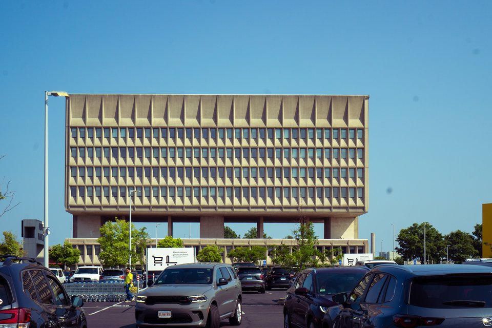 a grid-shaped building made of cement seated on plinths that make it appear to levitate