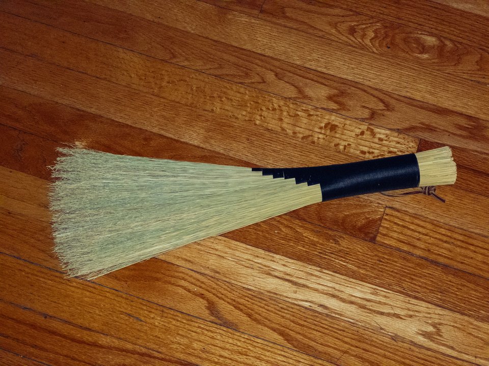 a small handmade broom with natural bristles and black thread wrapping