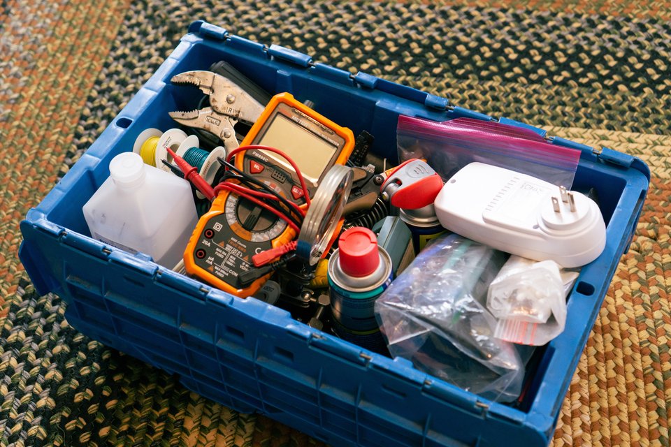 a plastic bin filled to the brim with tools and supplies