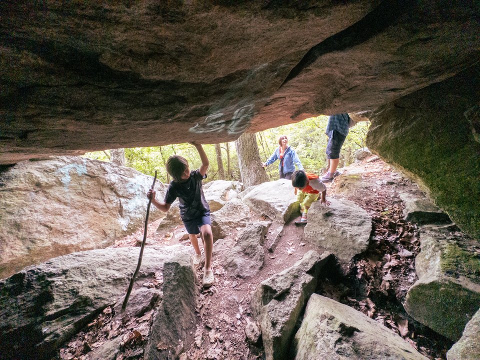 four people of various ages exploring a small cave