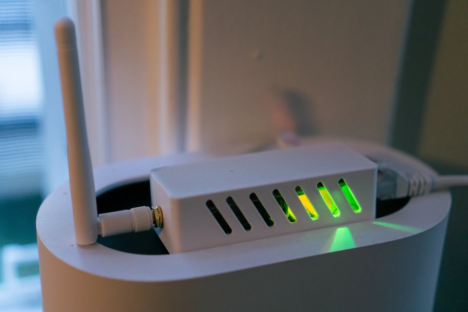 an electronic device inside a white 3D printed case with a green light shining from within