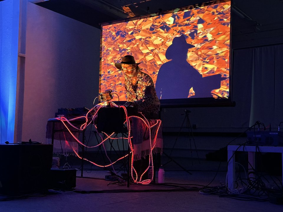 a person performing a dj set with projections and a cowboy hat