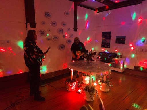two people performing noise music in a room with rainbow lights