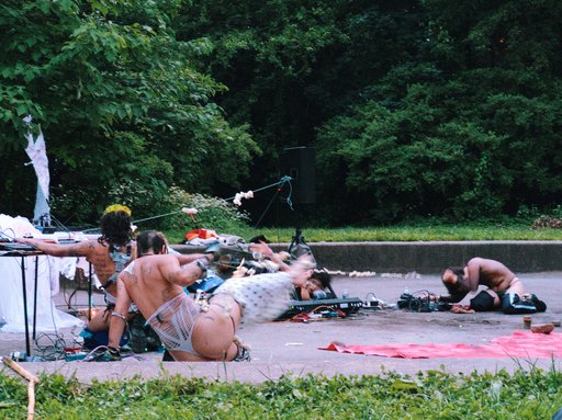 four people in costume in the park, crouched in various positions mid-dance